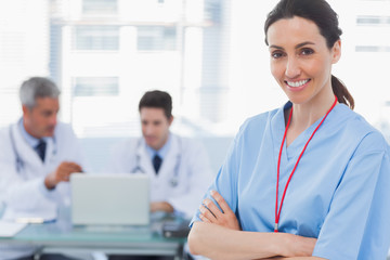 Fototapeta premium Doctors using laptop and a smiling nurse crossed her arms