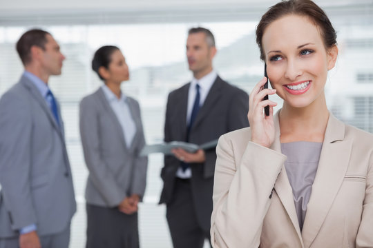 Smiling businesswoman calling while colleagues talking together