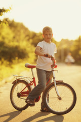 little funny boy with bike on sunset