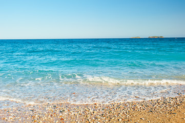 sea ​​wave rolls on the sand and shingle beach at sunrise