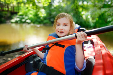 Happy little girl on a kayak on a river