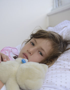 Ill child in bed with thermometer