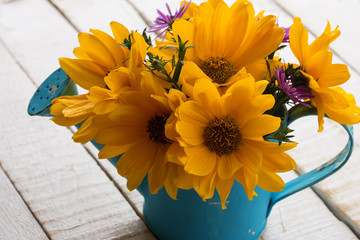Yellow fresh flowers in watering can