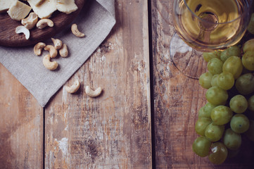 glass of white wine, grapes, cashew nuts and soft cheese