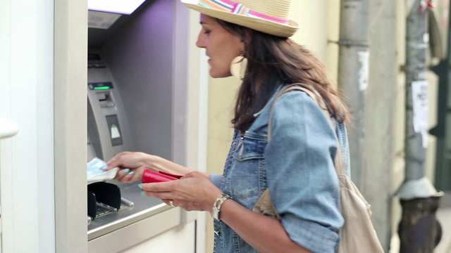 Happy woman taking cash from atm machine in the city