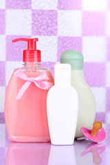 Baby cosmetics in bathroom on violet tile wall background