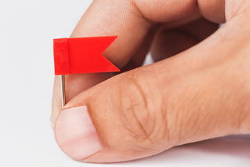 male hand with plastic red flags pin