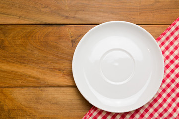 Empty plate on wooden tabletop with tablecloth