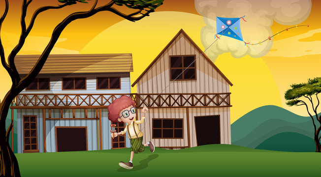 A boy playing with his kite in front of the wooden barnhouses