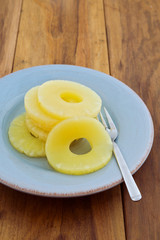 Pineapple in syrup on plate over wooden background