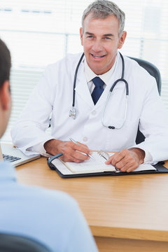 Cheerful doctor prescribing drug to his patient
