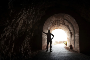 Young man stands relaxed in dark tunnel