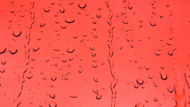 Drops of water running down red surface
