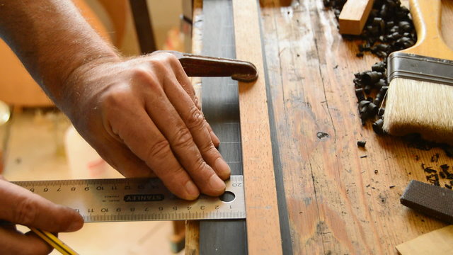 Luthier pointing the frets of a guitar