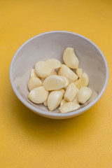 fresh peel garlic in a bowl yellow background