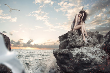 Portrait of sexy woman sitting on the rock at sea