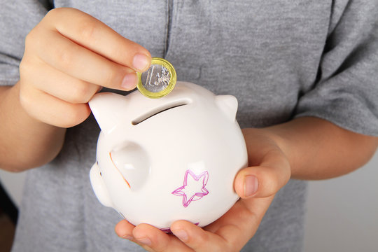 bambino mette un euro nel salvadanaio