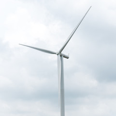 wind turbine in wind farm against cloudy sky