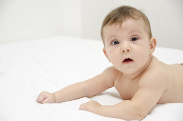 Cute baby on bed in home bedroom.