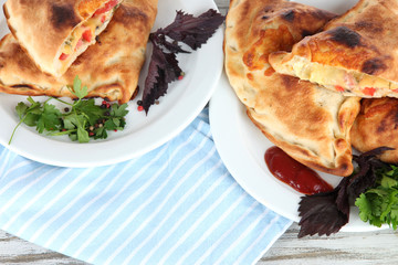 Pizza calzones on plates on napkin on wooden table