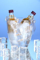 Minibar bottles in bucket with ice cubes,  on color background