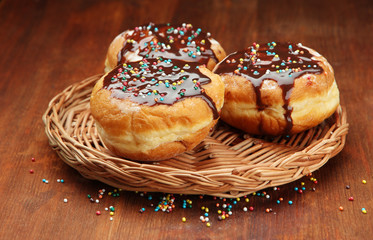 Tasty donuts with chocolate on wooden table