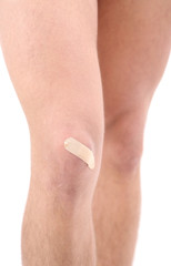 Young man with adhesive bandage on knee, isolated on white