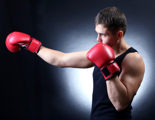 Fototapeta na wymiar Handsome young muscular boxer on dark background