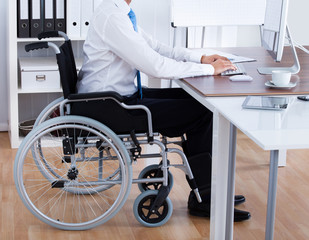 Businessman Sitting On Wheelchair And Using Computer