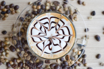 Panele Szklane Podświetlane  widok z góry na filiżankę latte art z ziarnami kawy na stole