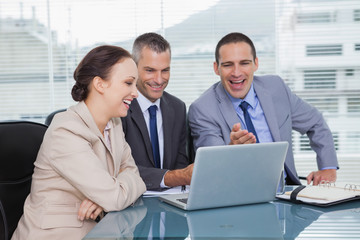 Naklejka premium Cheerful colleagues working together on their laptop