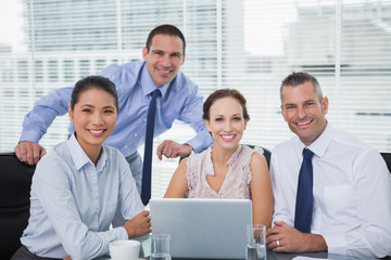 Fototapeta premium Cheerful colleagues around laptop posing