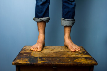 Man with bare feet standing on old wooden table