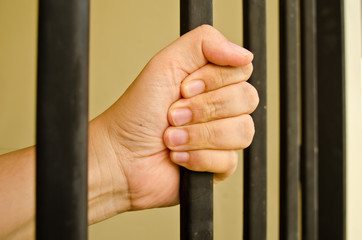 Hand of the prisoner on a jail bar