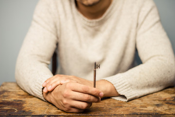 Man at table holding a key