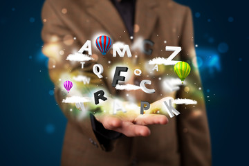 Young businessman presenting magical clouds with letters and bal