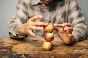 Man trying to balance apples on top each other