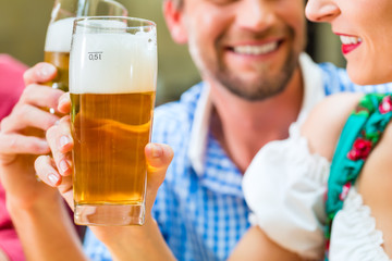 Freunde in Tracht trinken Bier in Bayern in Kneipe