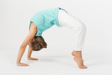 A girl in crab position makes gymnastic exercise