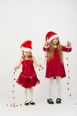Two little girls in caps Santa Claus holding a garland on hands