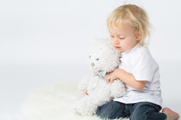 The little boy in jeans with a bear in his hands playing
