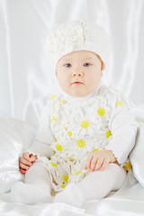 Portrait of little girl in white clothes, who sits