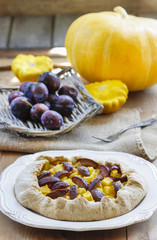 Plum and pumpkin galette on wooden table. Selective focus