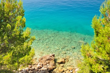 Naklejka na ściany i meble Beautiful beach with stones framed by trees. Tucepi, Croatia