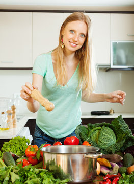 Positive Woman Adding Spices Or Salt To The Pot