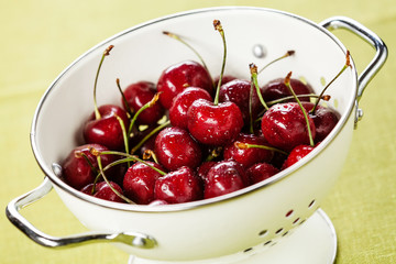 Wet ripe cherries in white colander