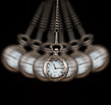 Pocket watch swinging on a chain black background