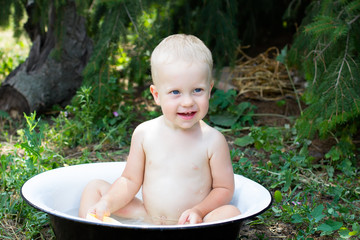 Baby boy (1 year) bathing outdoors.