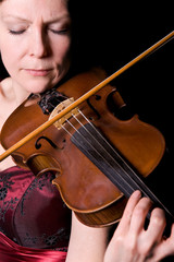 young woman plays the viola on black background