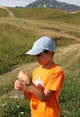 Naklejka na ściany i meble Young boy drinking water in a mountain landscape
